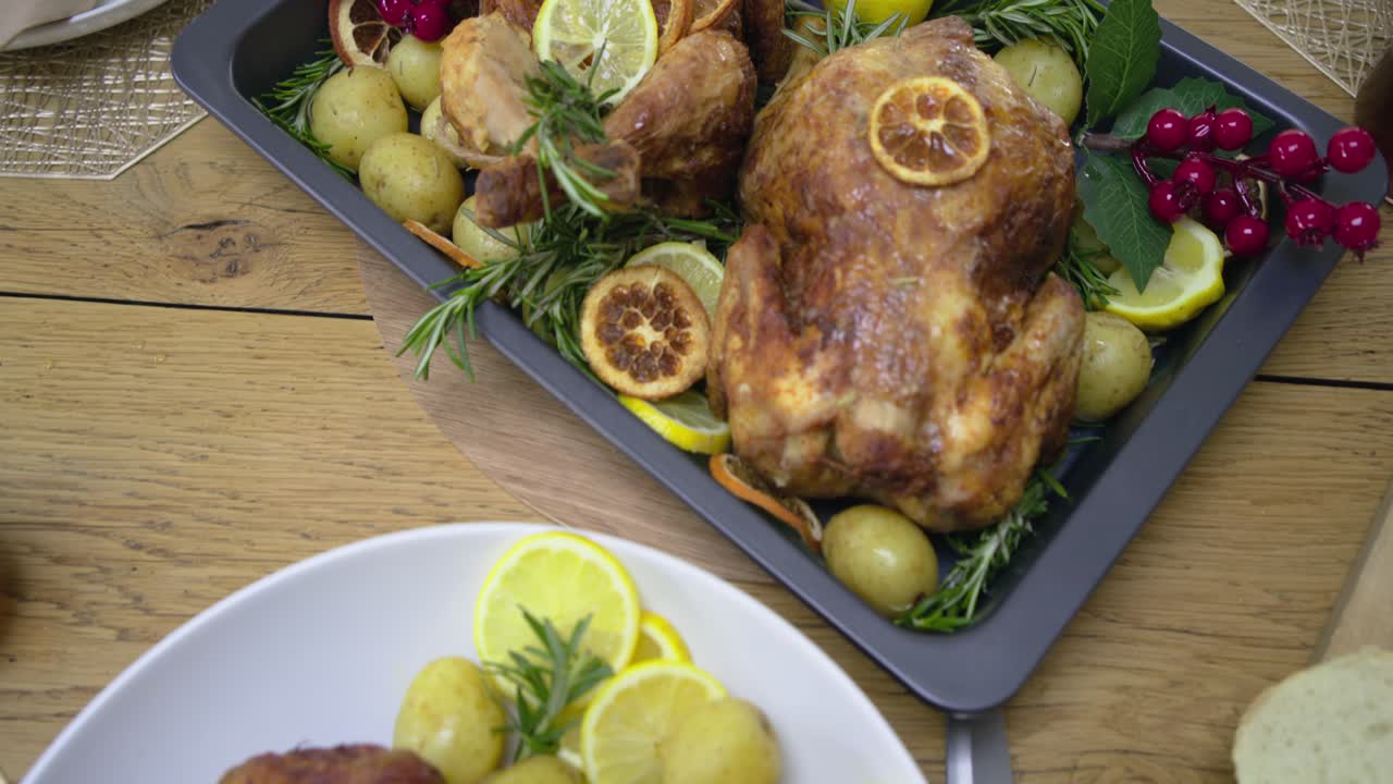 Camera panning across table from corn bowl to garnished drink, pan, plating chicken for serving