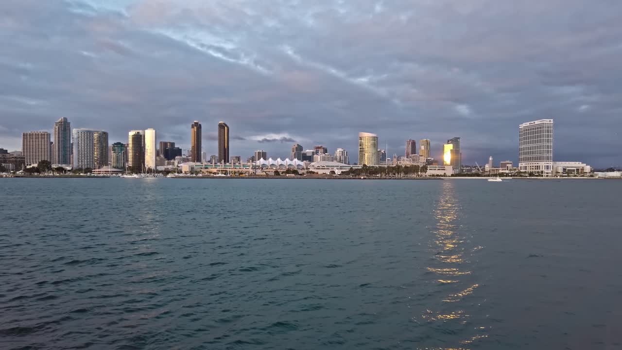 San Diego Convention Center and downtown view from a boat on local bay. Cloudy purple sky. Distance shot