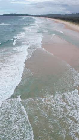 Vista-Aérea-Vertical-De-La-Orilla-Arenosa-De-La-Playa-De-Sebo,-Byron-Bay,-Australia-En-Un-Día-Nublado