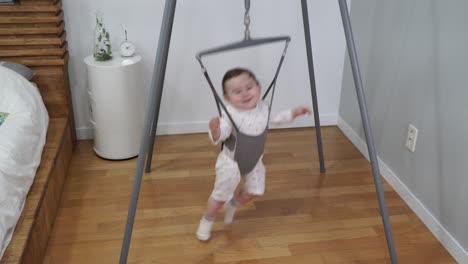 baby girl jumping from side to side smiling in a jolly jumper baby exercise equipment