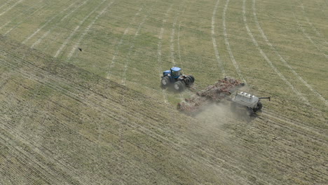 Seeding-machine-pulled-by-large-tractor-in-Canada-farmland,-sowing