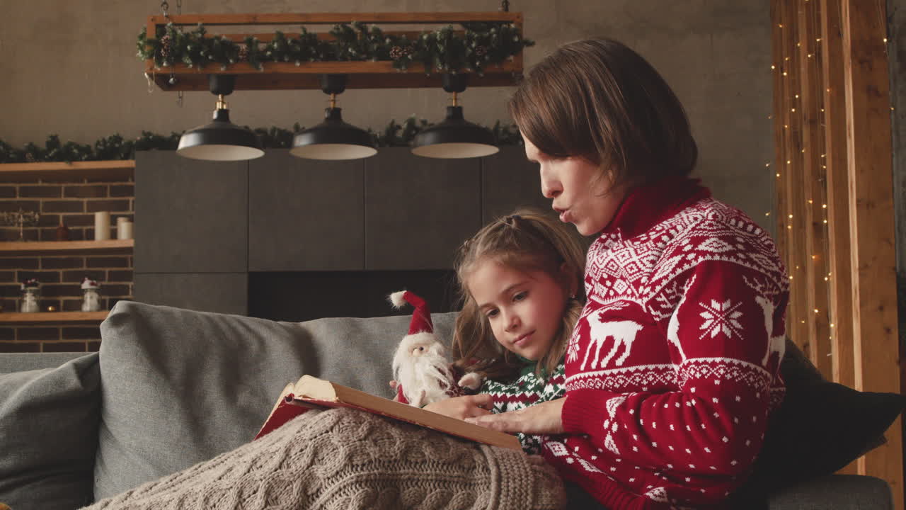 милая мама сидит на диване с очаровательной дочерью и читает ей сказку в день рождества дома 4