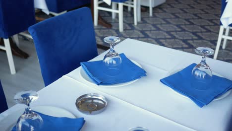 restaurant table setting with blue napkins and wine glasses