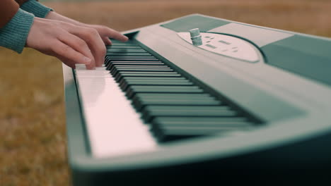 tocando el piano, teclado afuera con un abrigo en primer plano
