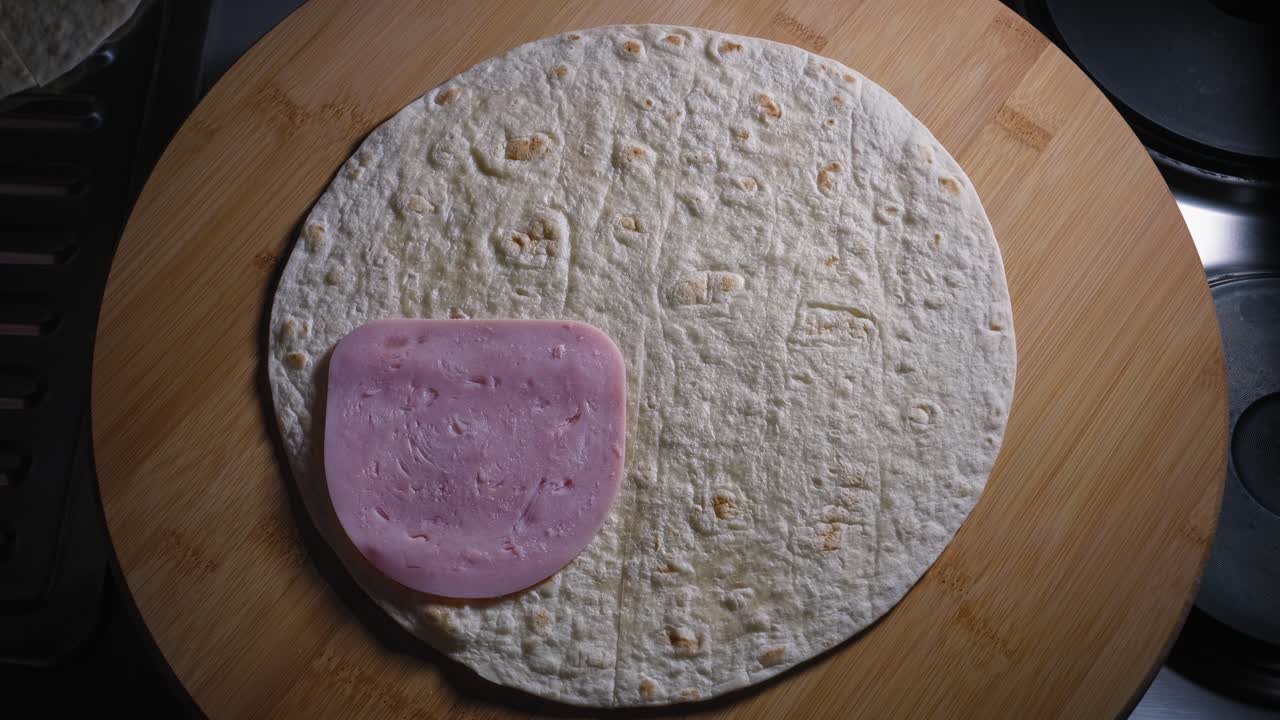 poniendo jamón y queso separados en tortilla con la mano izquierda y corrigiendo el diseño del queso