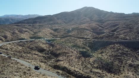 Vehicles-driving-on-desert-highway-on-sunny-hot-day-in-California,-aerial-drone-shot