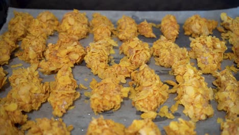 raw chicken in cornflakes coating in a baking tray