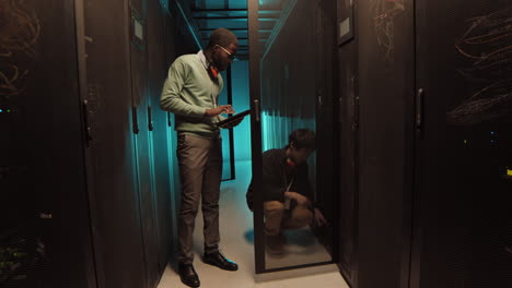 african-american it engineer asking colleague question in data center