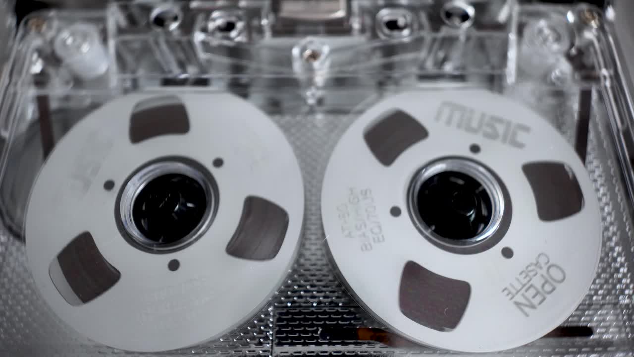 Showing nostalgia and analog audio revival with a close up view of cassette tape reels spinning