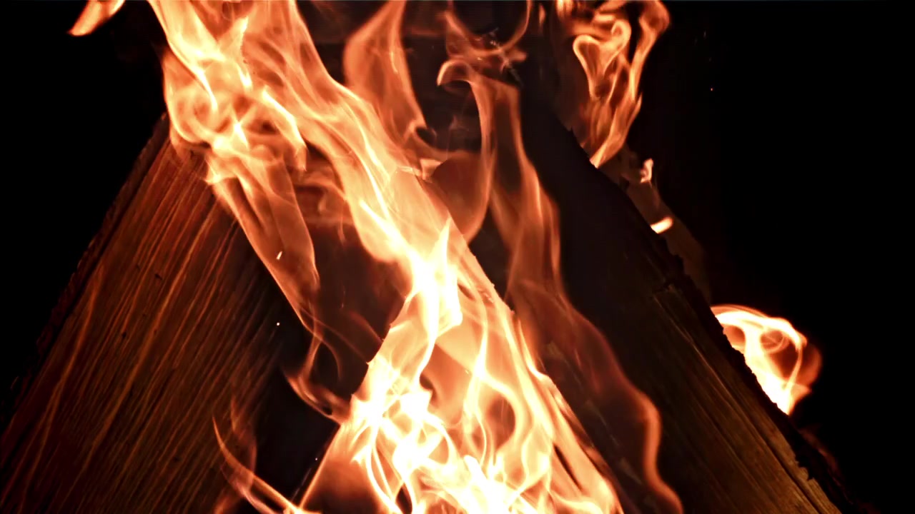 Calde fiamme di falò che bruciano intensamente su tronchi di legno.