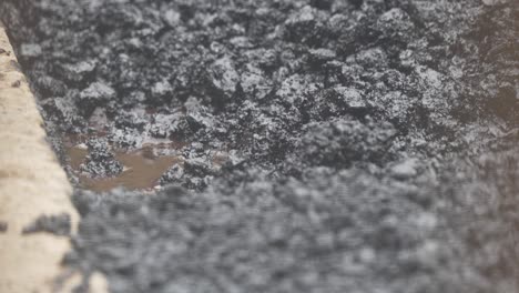 close up shot of hot gravel being poured onto pothole and being raked