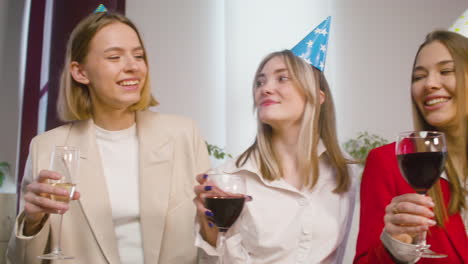 feliz grupo multiétnico de colegas femeninas brindando con champán y vino en la fiesta de la oficina