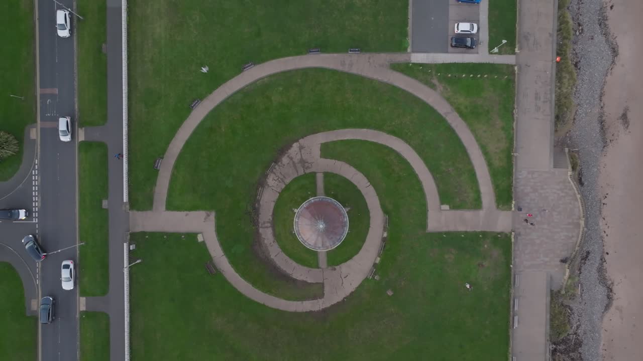 Overhead view of geometric circular pathways in grassy coastal park