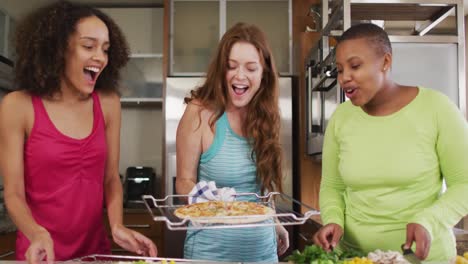 diverse group of happy female friends preparing pizza at home