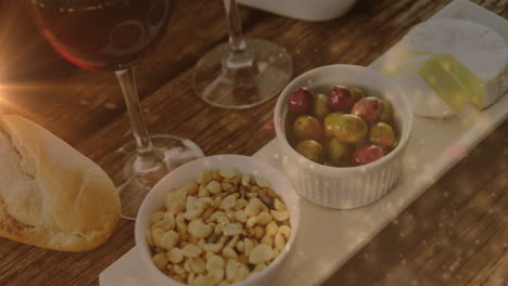 animation of lights over wine and snacks arrangement on wooden table