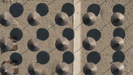 woven beach parasols and boardwalk on hot sand form repeating pattern