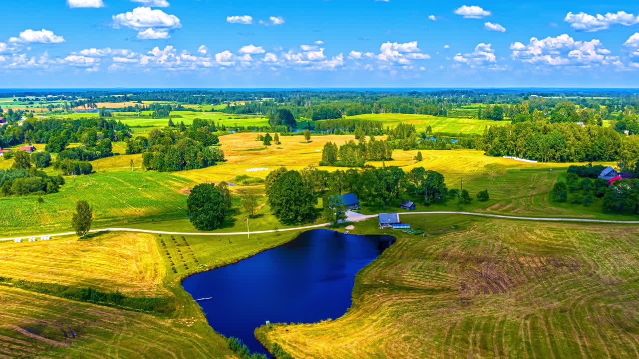 Bright golden farmland fields under vivid blue sky at sunset with cloud shadows crossing idyllic rural ponds