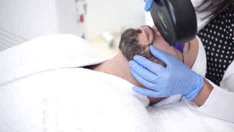 man receiving laser hair removal treatment on his face
