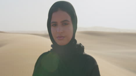 Portrait-Of-A-Beautiful-Muslim-Woman-With-Hijab-Looking-At-Camera-In-A-Windy-Desert-1