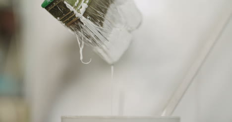 young man painting wooden board with a white paint