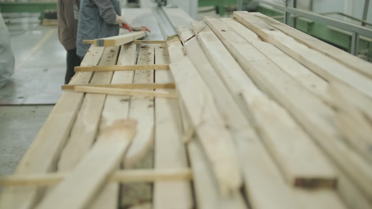 Operaio che spazza via la segatura dalle tavole di legno in una segheria