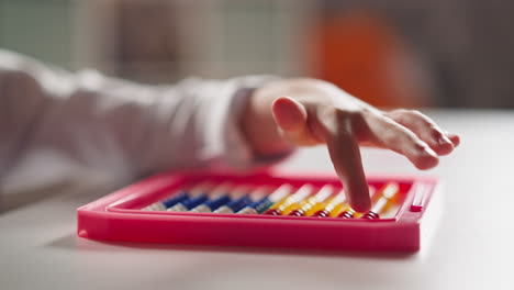 little girl hand counts moving small beads on toy abacus