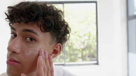 applying skincare cream, young person with closed eyes enjoying self-care routine