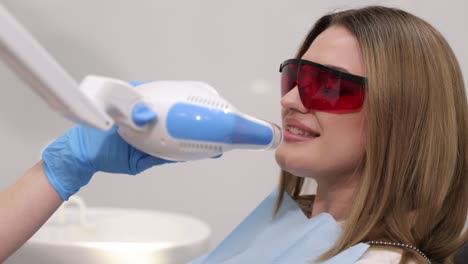 woman undergoing professional teeth whitening treatment while sitting comfortably under dental lamp.
