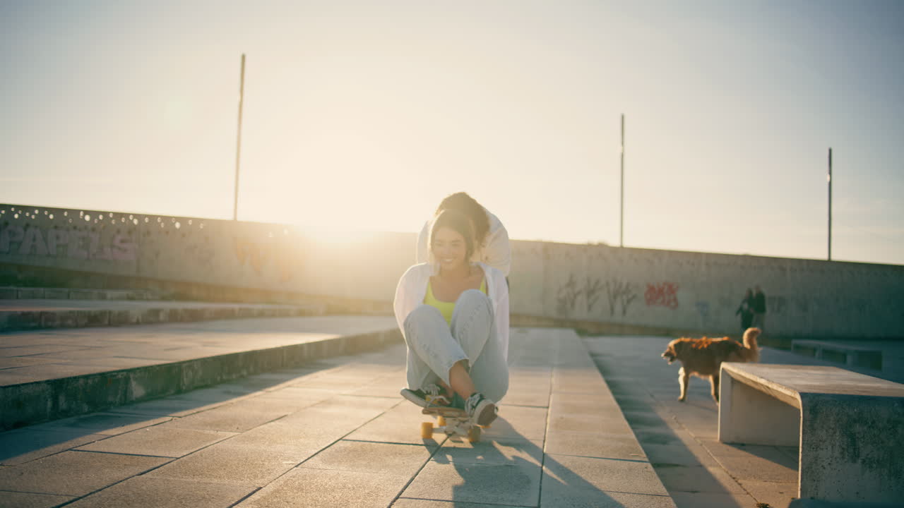 Joyful lovers enjoying skateboard ride sunbeams street. Skaters riding longboard