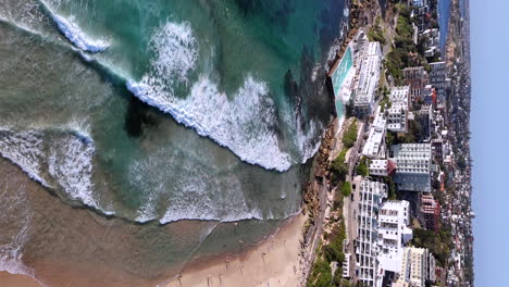 cinematic aerial view of bondi beach and ocean pool, highlighting the natural beauty of this iconic australian coastal landmark. vertical drone footage.