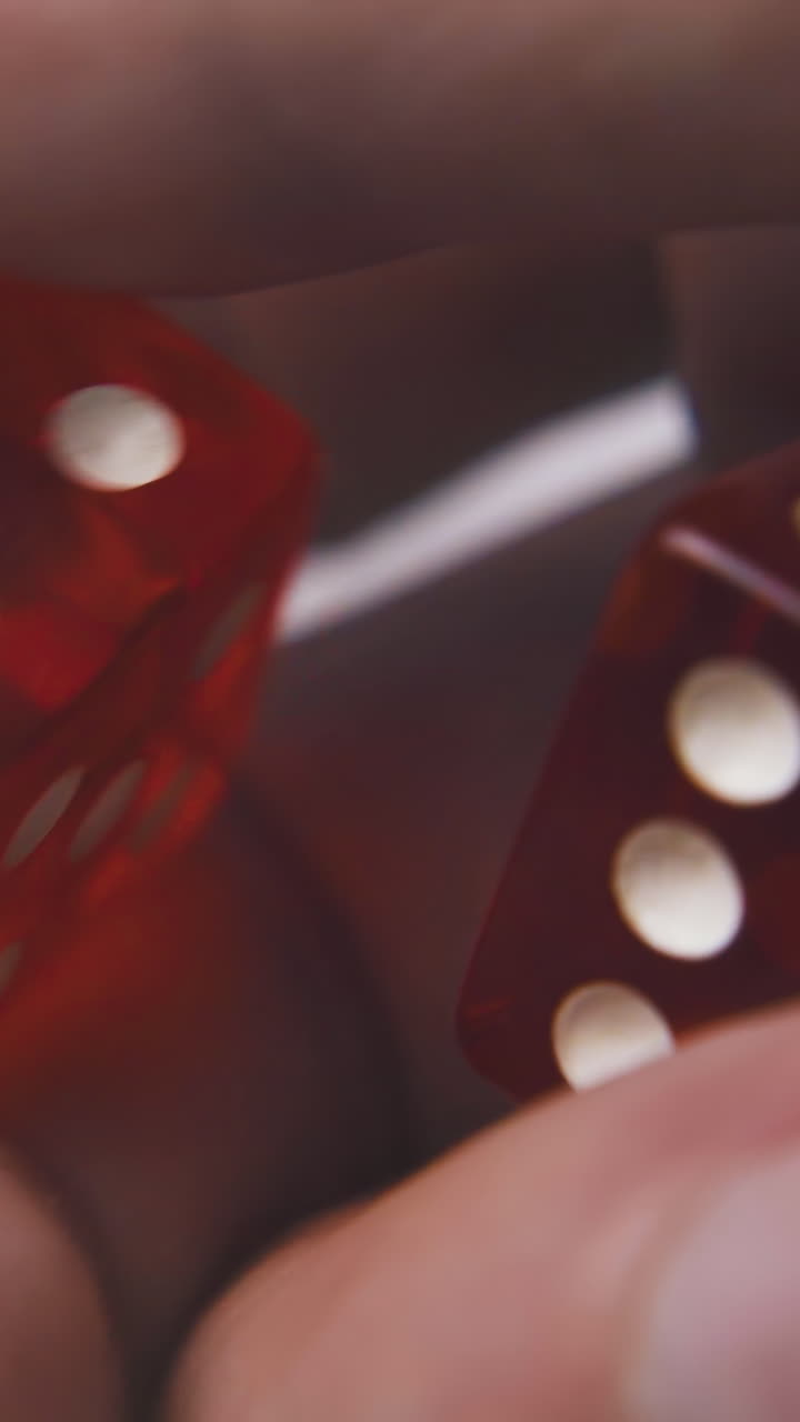 young man hand throws red transparent plastic dices with white spots to light surface macro