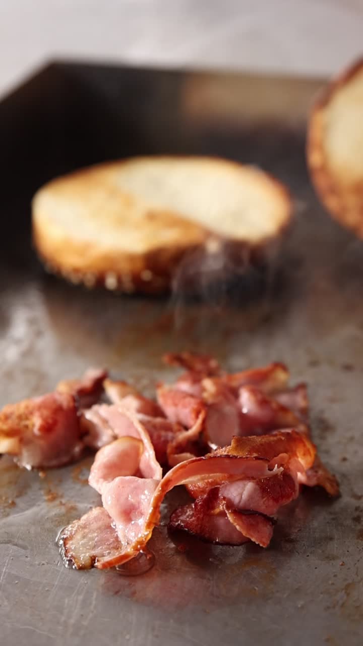 Pancetta che frigge su una piastra calda con panini tostati