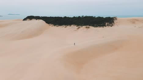 Sandboarder-Caminando-Solo-En-Grandes-Dunas-De-Arena-Cerca-De-La-Playa-Tropical-De-Garopaba,-Santa-Catarina,-Brasil