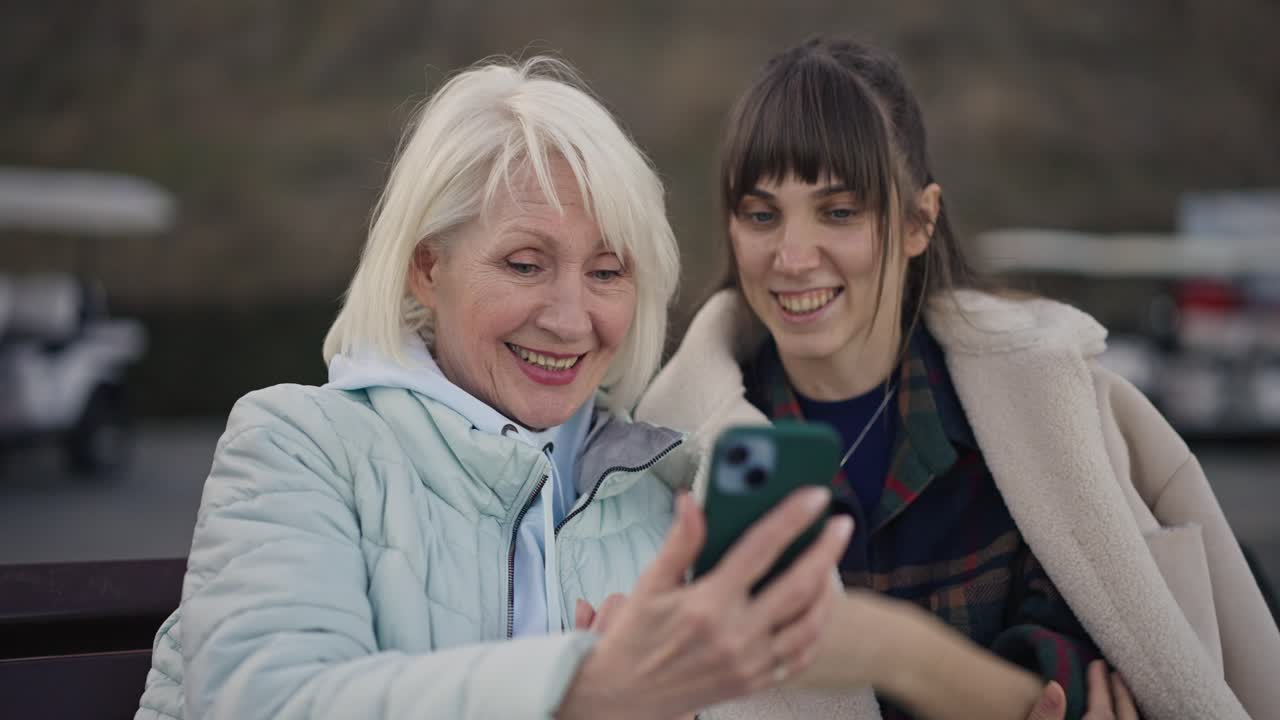 Donna anziana e giovane adulto che usano uno smartphone insieme
