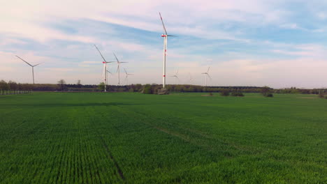 Scenic-aerial-view-of-wind-turbines-farm-in-green-field-sunset-time-in-Brandenburg-countryside,-Berlin,-Germany