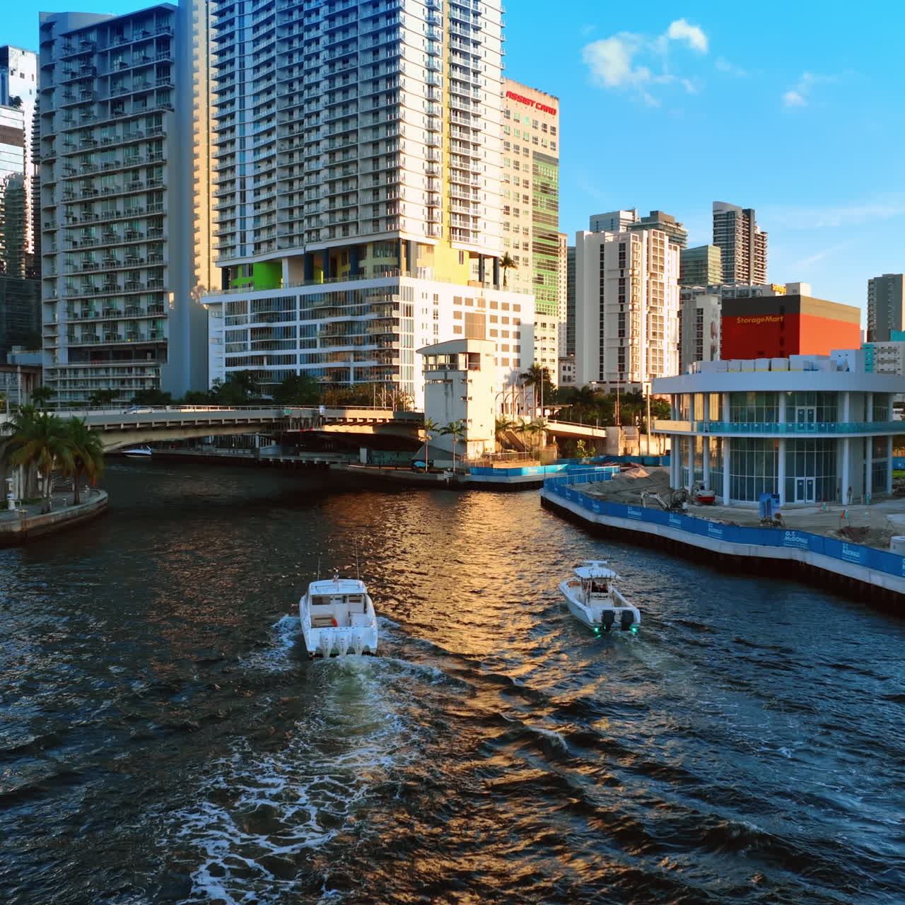 Following two motor boats gong by the river to the little bridge. Picturesque view of Miami downtown, Florida, USA.