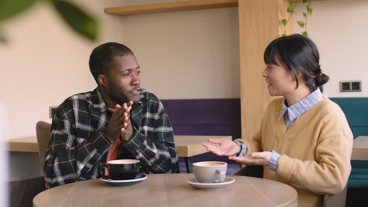 Man And Woman Talking Together While Sitting At Table In A Coffee Shop