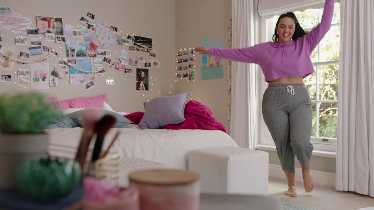 una adolescente con sobrepeso feliz bailando en el dormitorio divirtiéndose bailando celebrando el fin de semana sintiéndose positiva vistiendo pijama en casa