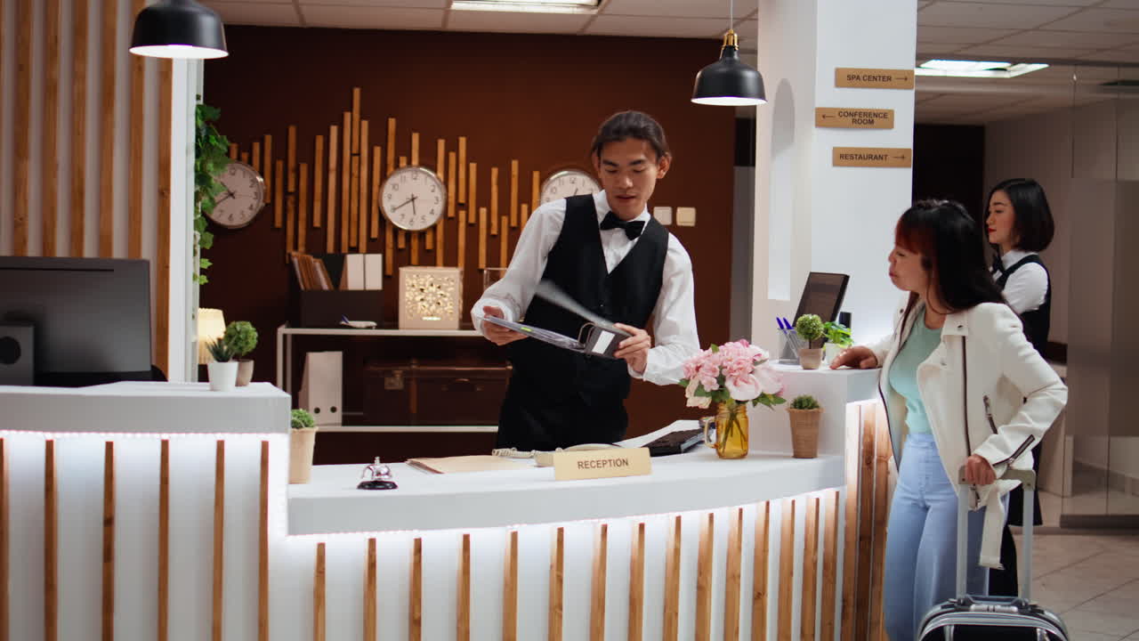 cliente asiático preguntando al conserje del hotel sobre el alojamiento
