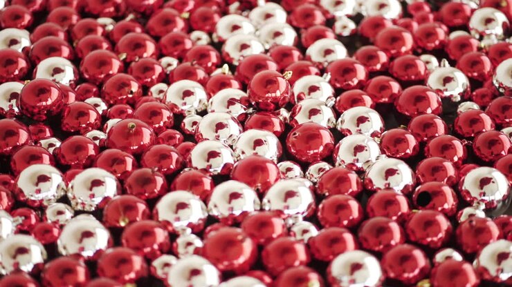 Red and silver Christmas bulbs scattered and clustered on the floor - High angle slide slow motion shot