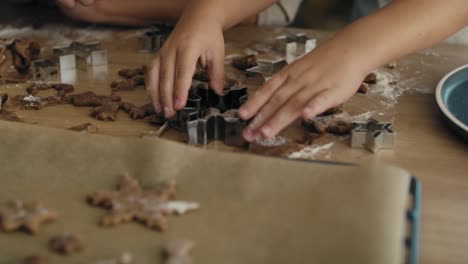 detalle de una mujer caucásica poniendo galletas de pan de jengibre crudas en la bandeja de horneado.