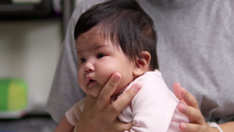 tapping the back of a newborn infant, the mother is helping her child to burp to release some gas after having its meal