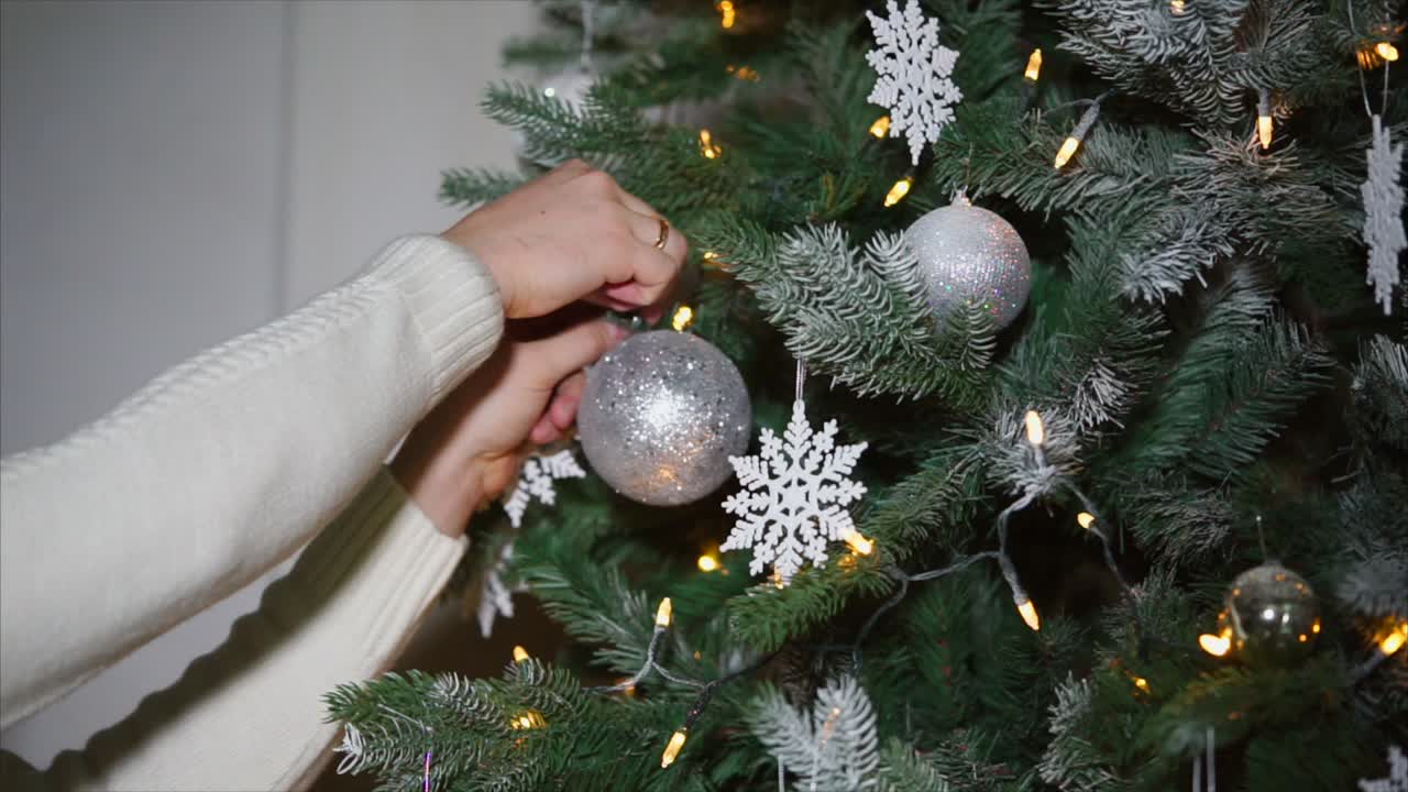 Woman Decorating a Christmas Tree with Silver Ornaments