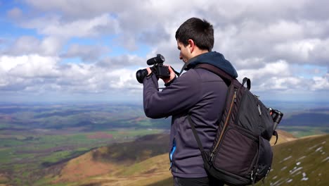videógrafo grabando un video en una caminata en la cima de la montaña pen y fan, gales