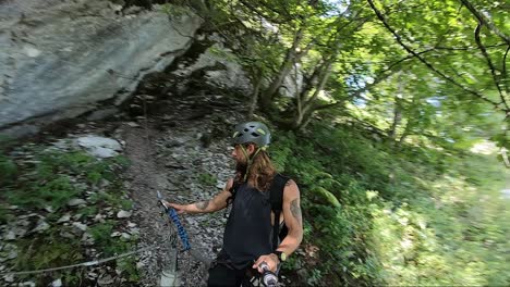 joven en forma caminando por un camino de tierra en el bosque al lado de un gran acantilado y roca en su montaña escalando caminata por murren ferrata en suiza