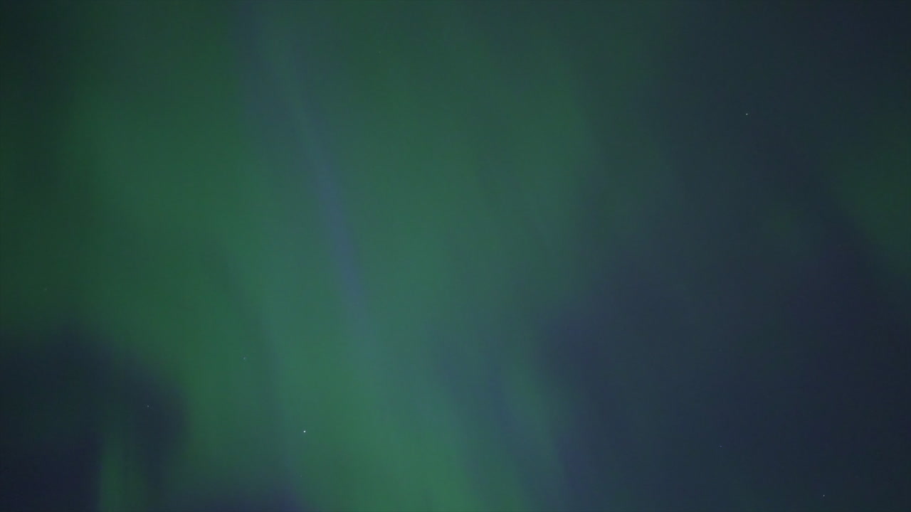 espectáculo hipnótico de las luces del norte bailando con gracia sobre un bullicioso horizonte de la ciudad, mostrando la aurora boreal, el paisaje urbano, la belleza celestial, y la maravilla nocturna, rica en verde