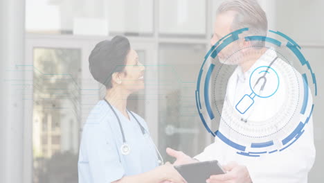 doctor and nurse sharing tablet medical data in hospital corridor with digital interface