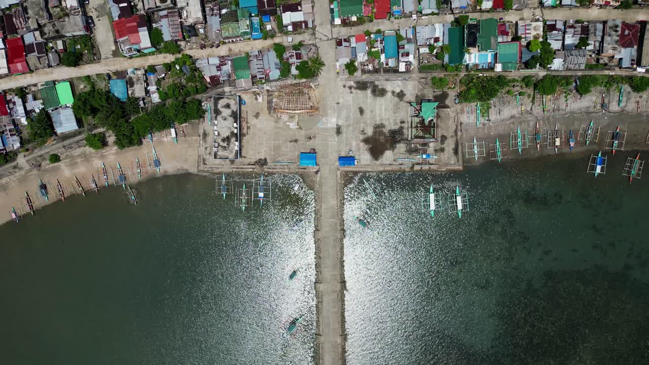 Aerial bird's eye view of traditional Filipino fishermen bangka boats docked along coastal barangay town at Codon port, Catanduanes, Philippines
