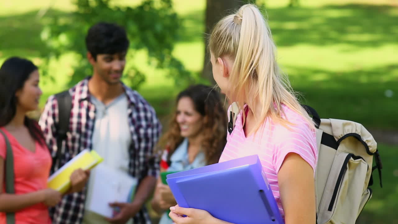 estudiante sonriendo a la cámara con amigos de pie detrás de ella
