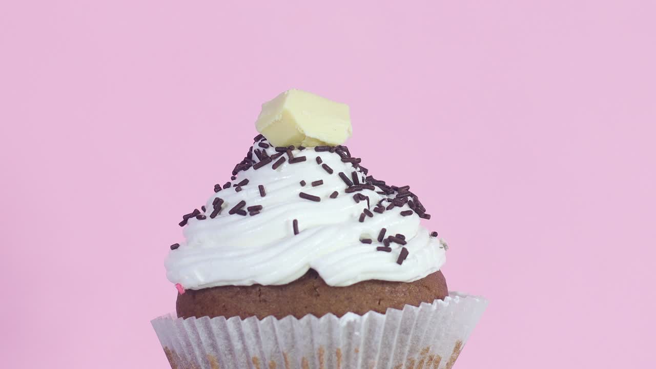 Rotating chocolate cup cake with cream and one white chocolate on the top. Close up